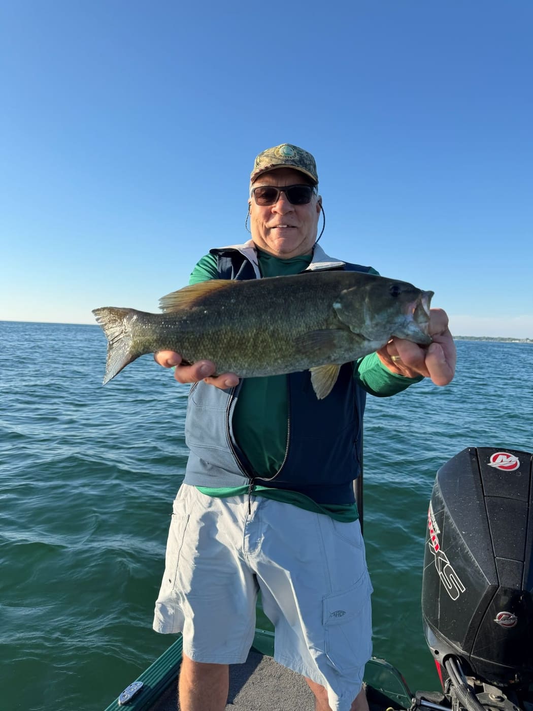 A client with a heavy smallmouth bass on open water